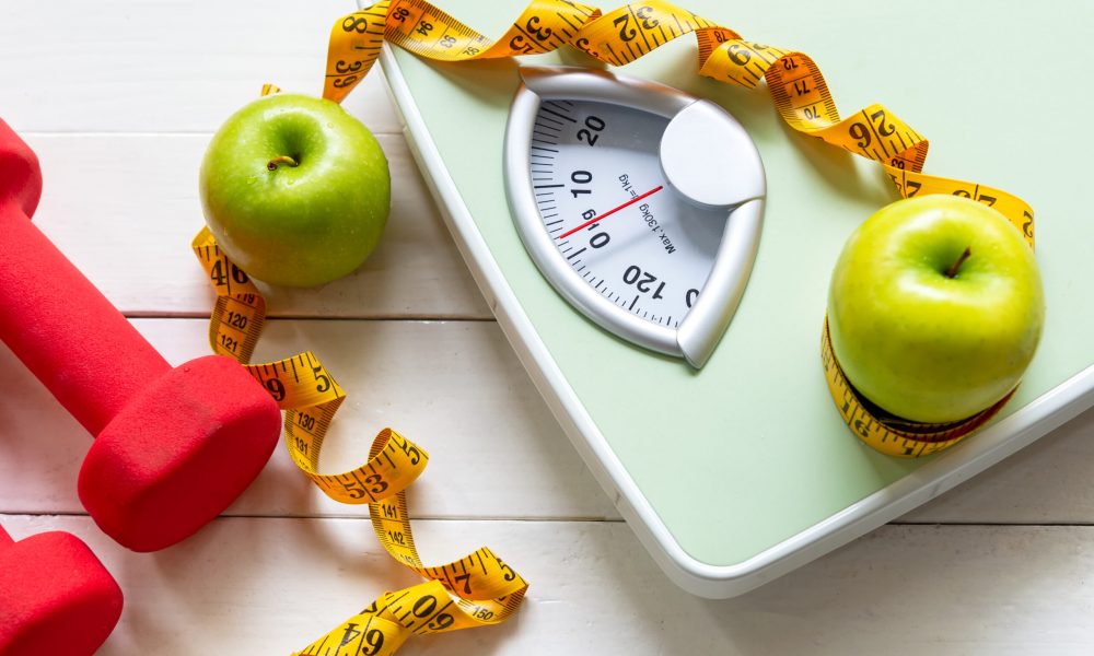 Diet and Healthy life loss weight Concept. Green apple and Weight scale measure tap with fresh vegetable and sport equipment for women diet slimming.